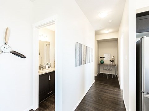 a kitchen and a hallway with a refrigerator and a sink
