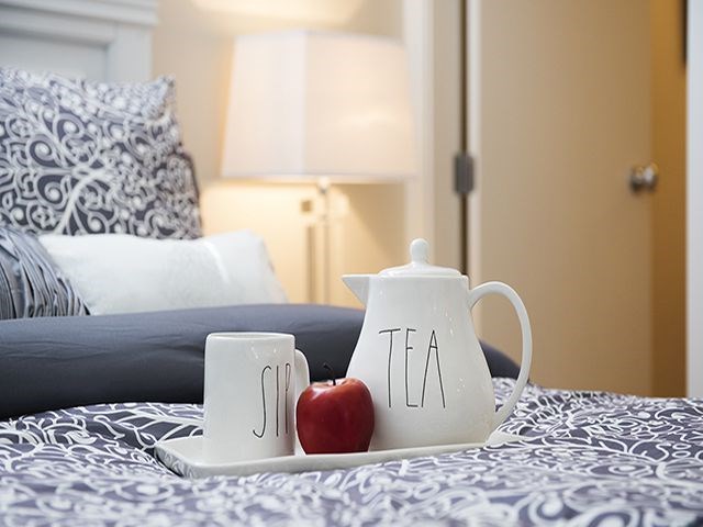 a tray with a tea kettle and an apple on a bed