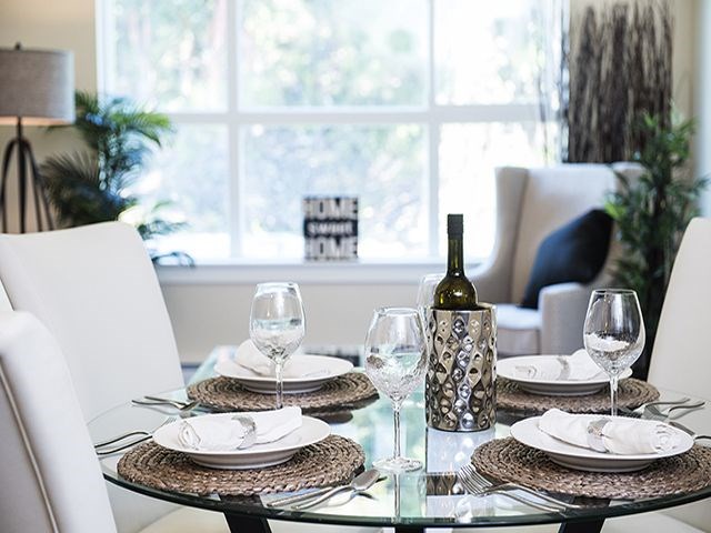 a glass table with plates and glasses and a bottle of wine