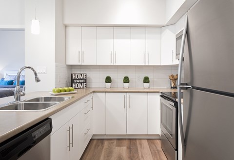a white kitchen with stainless steel appliances and a sink