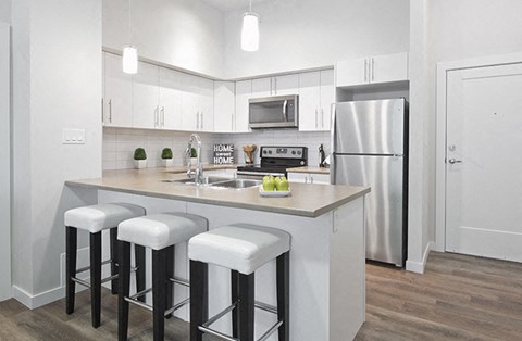 A kitchen with white cabinets and a white fridge.