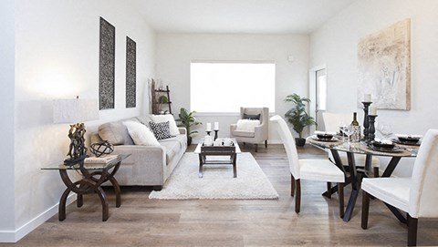 A living room with a white couch, a coffee table, and a dining table with chairs.
