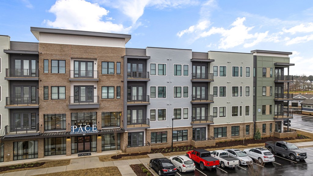 A row of modern apartment buildings with cars parked in front.