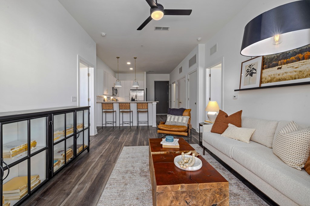 A modern living room with a large couch, a coffee table, and a balcony with glass railings.