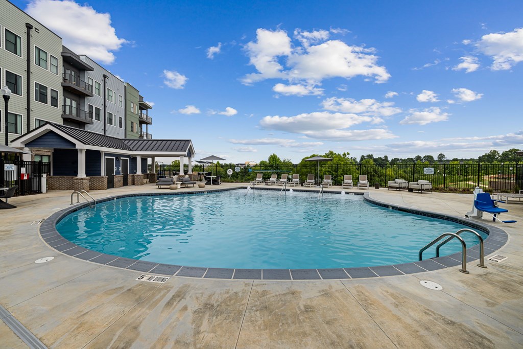 A large outdoor swimming pool surrounded by a wooden deck and a building in the background.