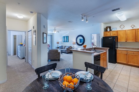 a dining room table with a bowl of fruit on top of it and a kitchen