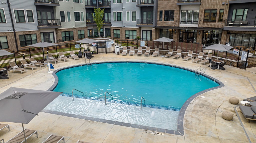 A large outdoor swimming pool surrounded by lounge chairs and umbrellas.