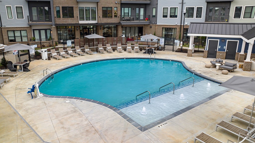 A large swimming pool surrounded by lounge chairs and umbrellas.