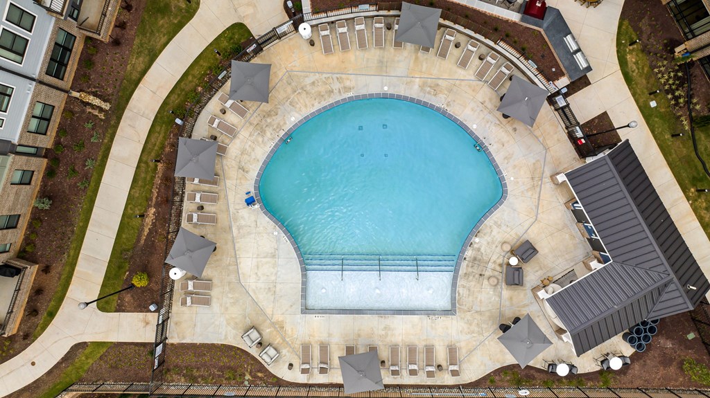An aerial view of a swimming pool surrounded by lounge chairs and umbrellas.