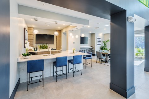 a kitchen and dining area with blue chairs and a counter with a sink