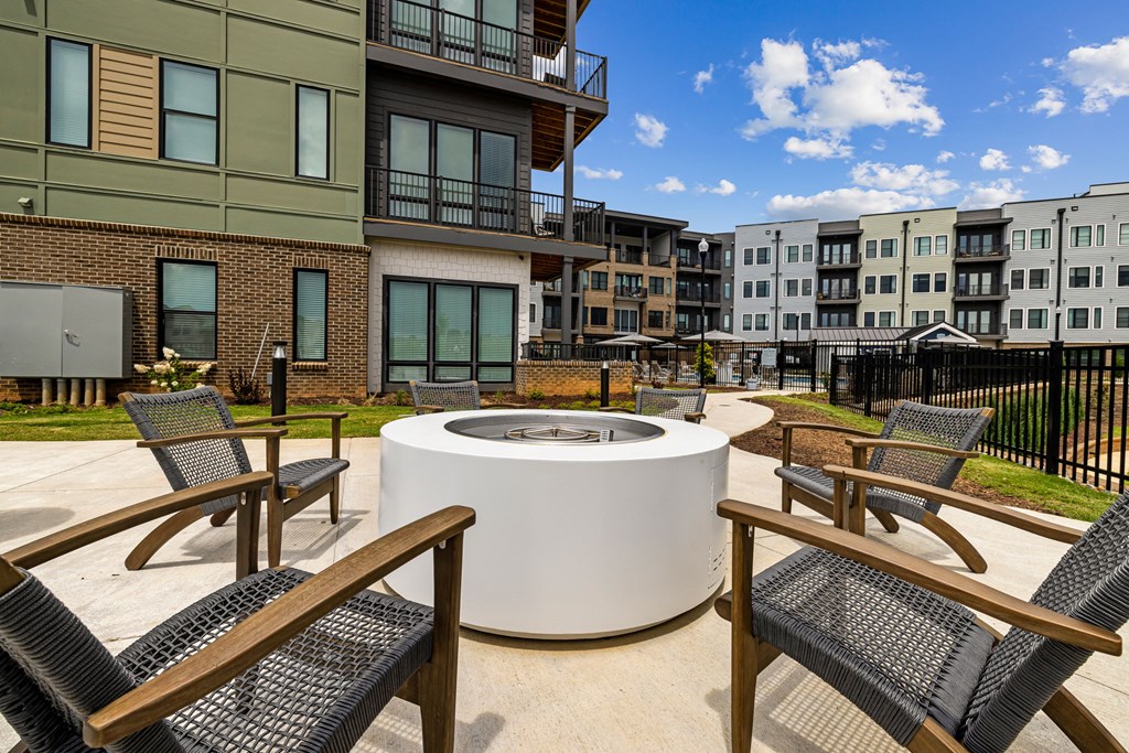 A white circular table is surrounded by chairs in a courtyard.