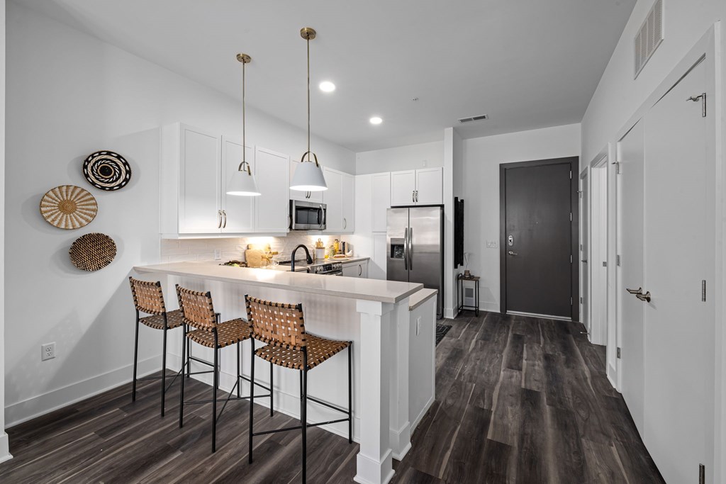 A kitchen with a white counter and brown chairs.