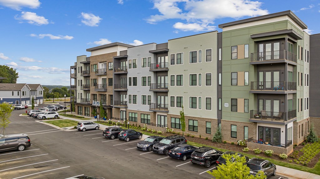 A parking lot in front of a multi-story apartment building.