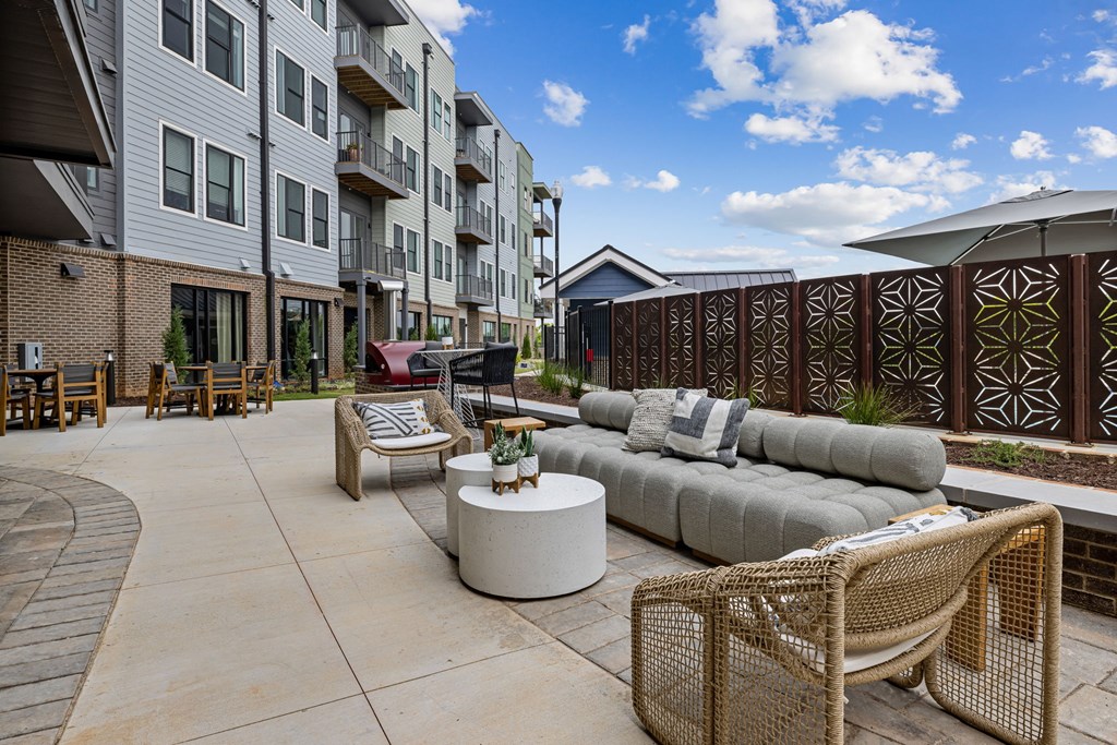 A patio with a couch, chairs, and a table with a plant on it.