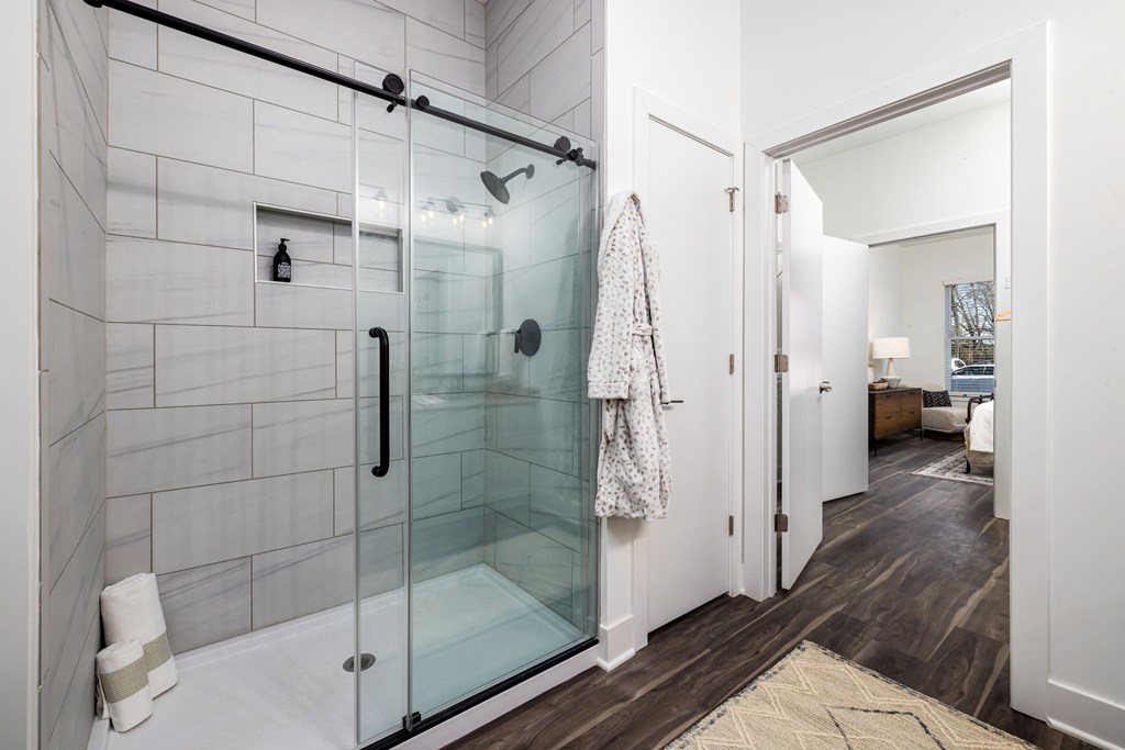 A bathroom with a glass shower door and a towel hanging on the door.