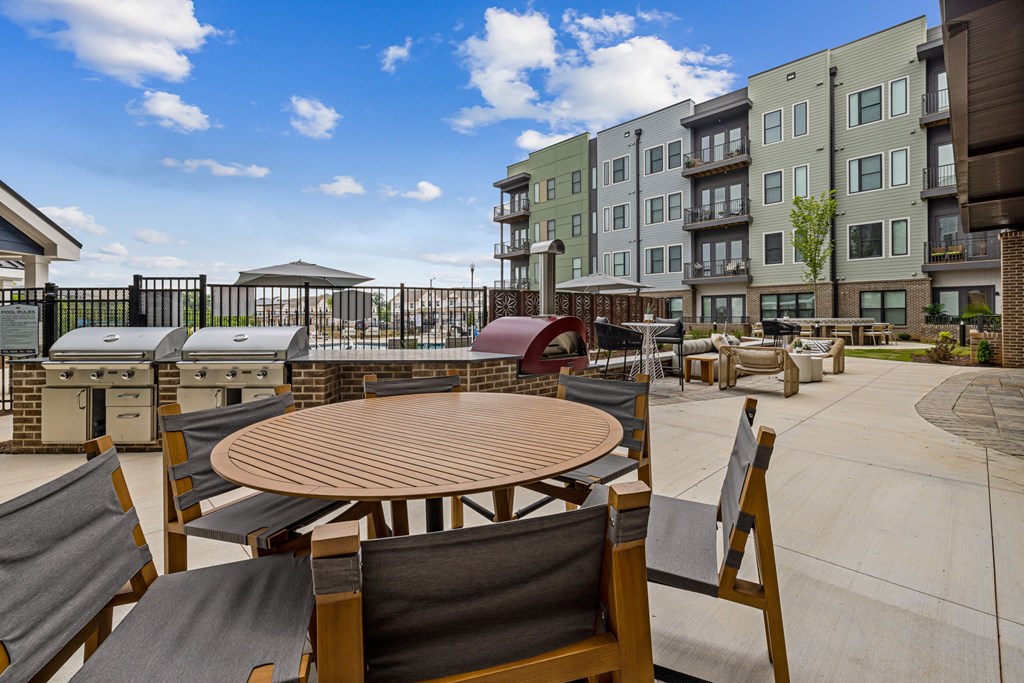A patio with chairs and a table is surrounded by apartment buildings.