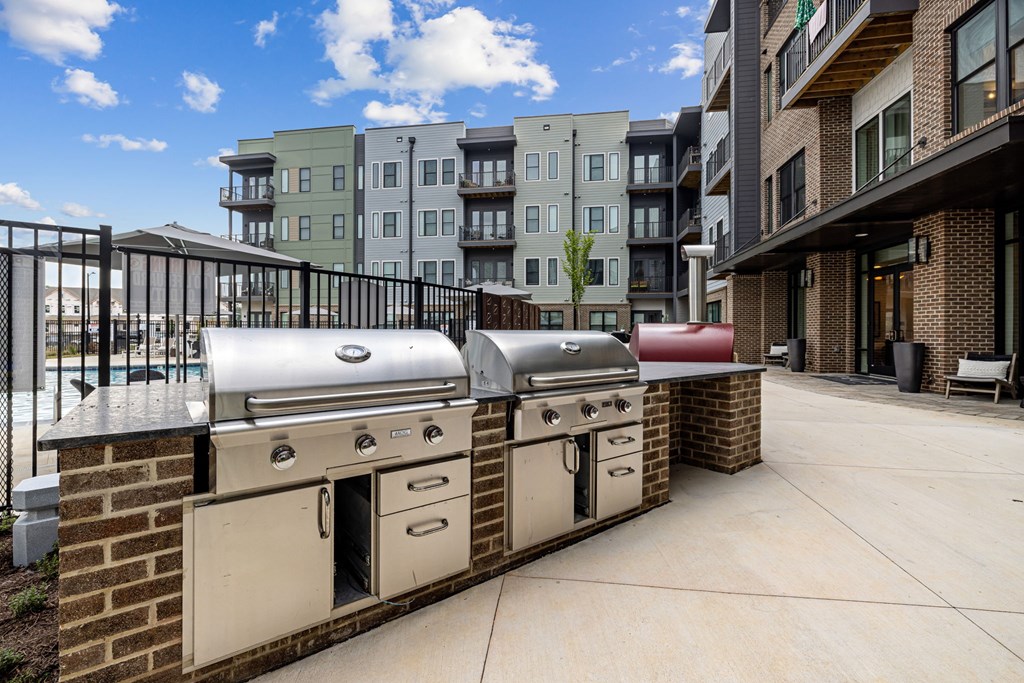 A row of modern apartment buildings with a row of outdoor BBQs in front.