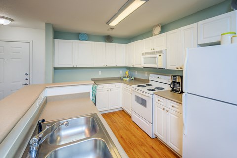 a kitchen with white cabinets and a sink and a refrigerator