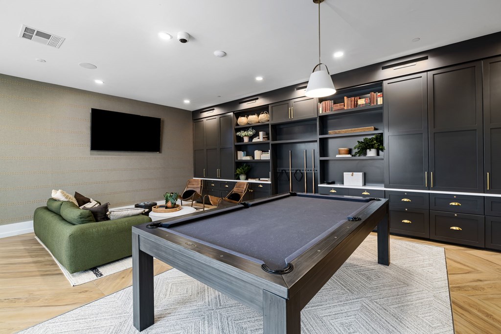 A pool table is in the middle of a room with a TV and a sofa.