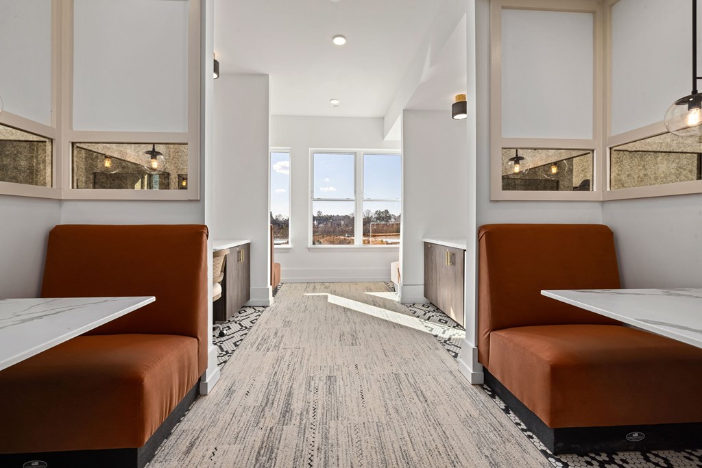 A long, narrow room with orange booths and a carpeted floor.