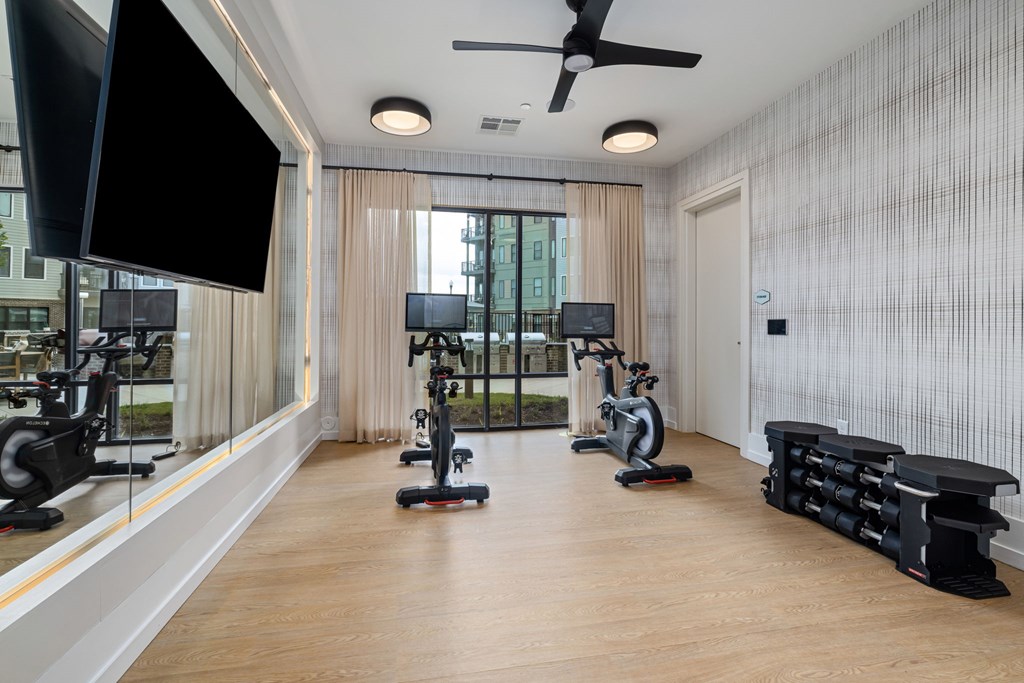 A spacious room with a row of exercise bikes and a television.