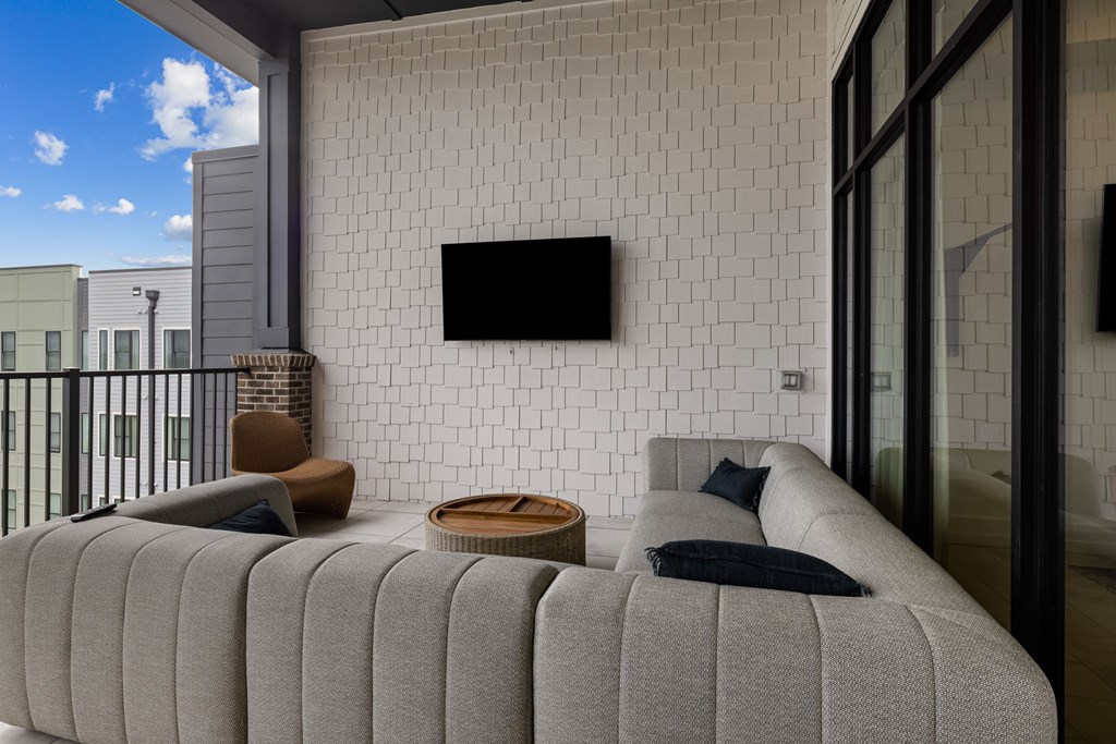 A modern living room with a grey sofa and a flat screen TV mounted on the wall.