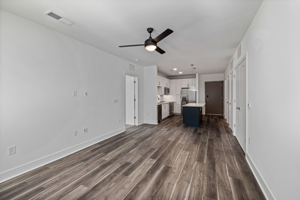 A room with a ceiling fan and wooden flooring.
