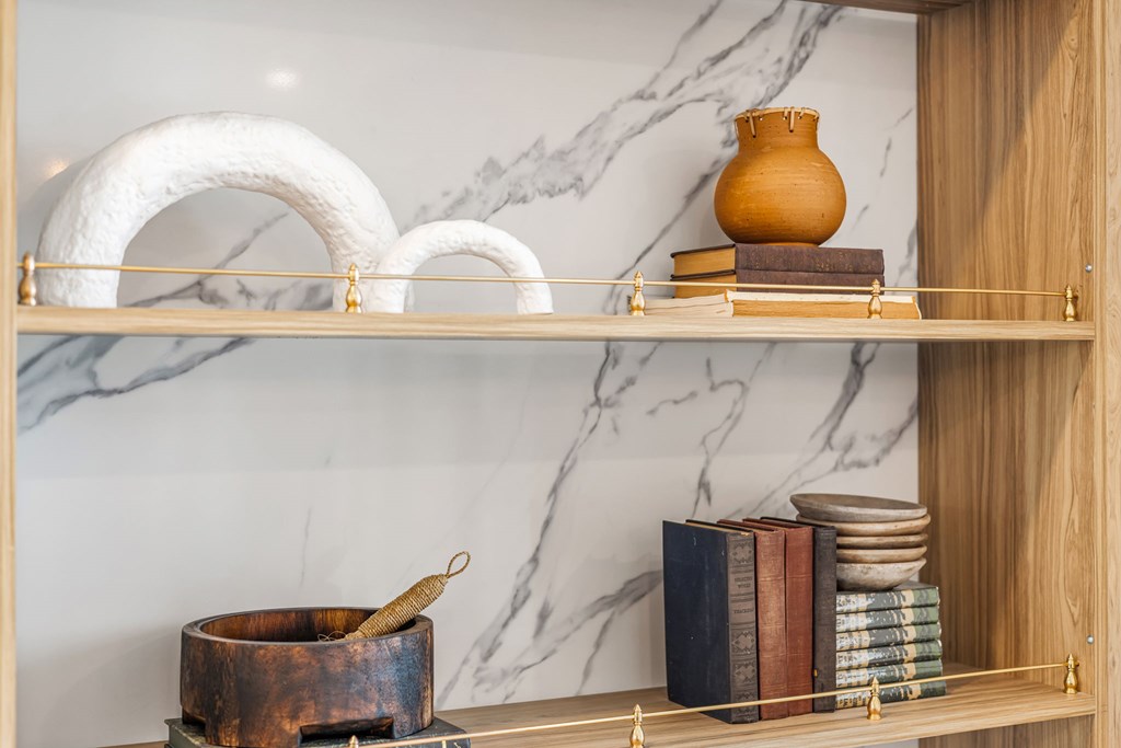 A shelf with a white vase, a brown vase, and a stack of books.