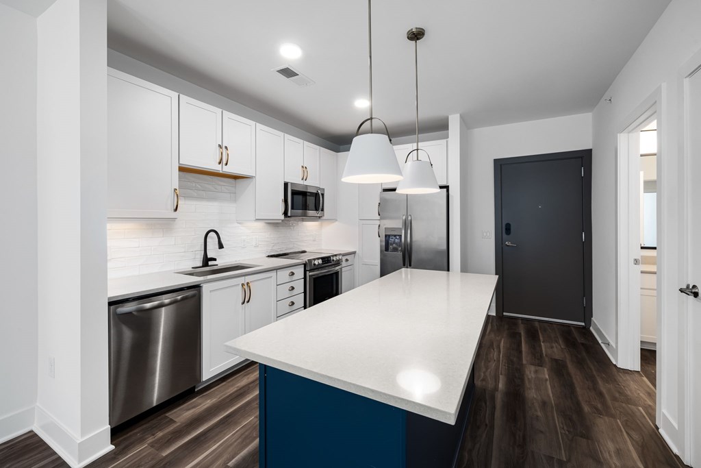 A modern kitchen with a white countertop and stainless steel appliances.