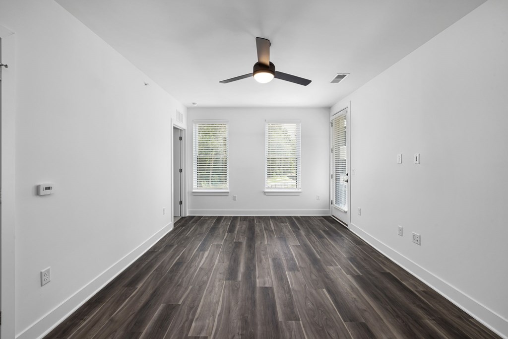 A room with a ceiling fan and wooden flooring.