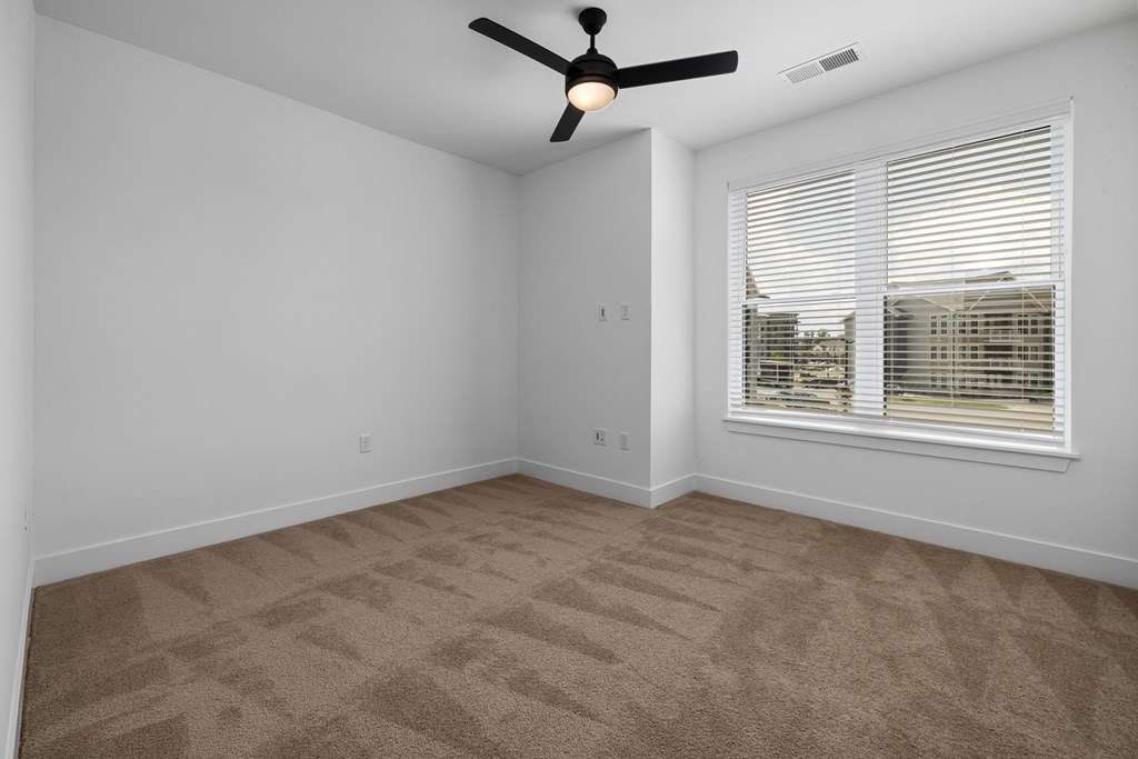 A room with a ceiling fan and carpeted floor.
