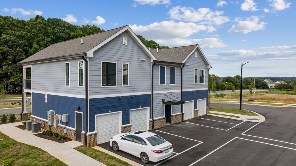 A white car is parked in front of a blue and white building.