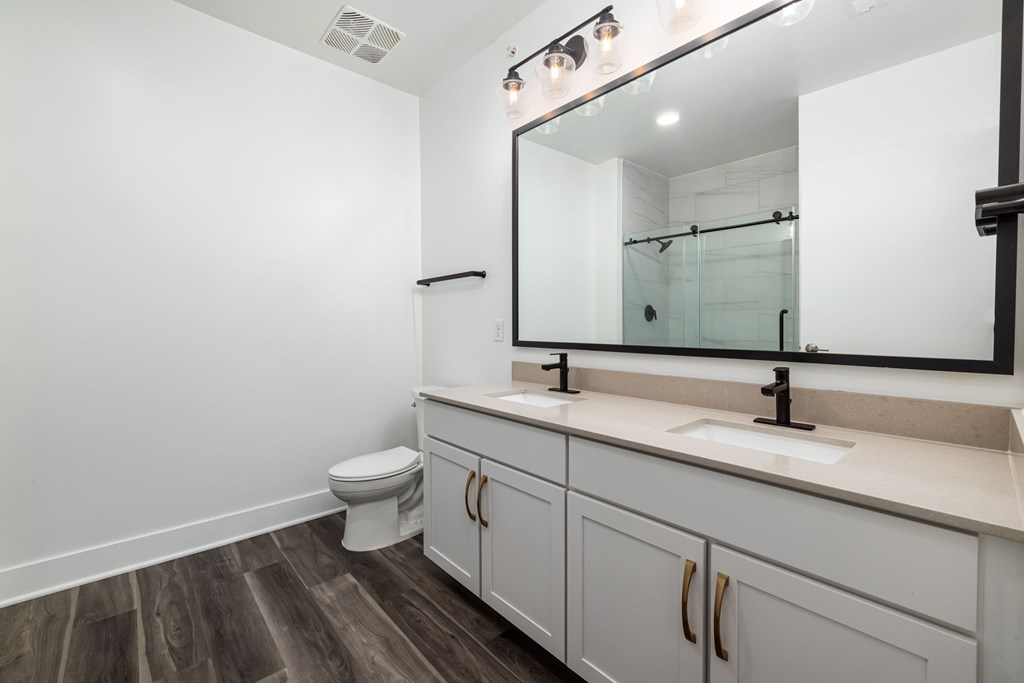 A bathroom with a toilet, sink, and mirror.