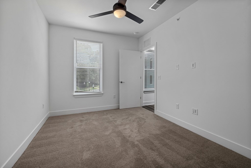 A room with a ceiling fan and carpeted floor.