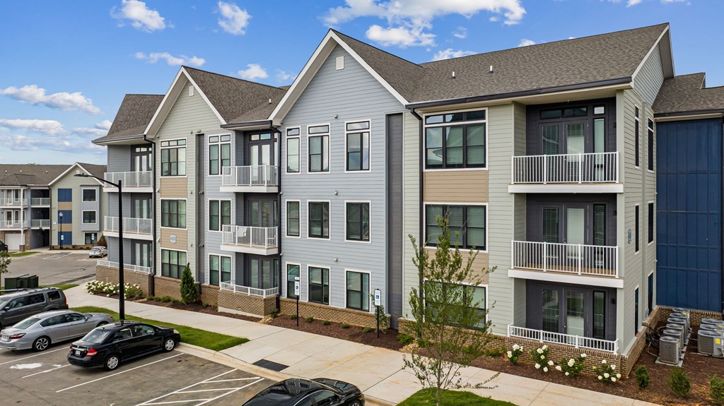 A large apartment complex with a parking lot in front.