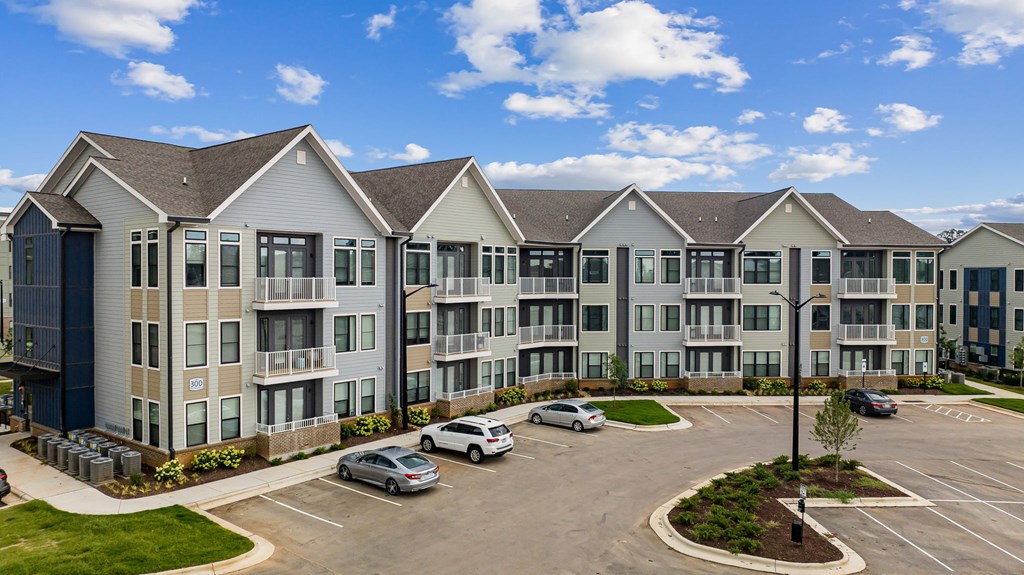 A large apartment complex with a parking lot in front.