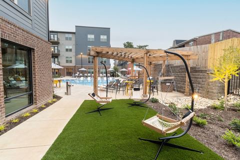 the yard with swings and a pool at the trilogy apartments