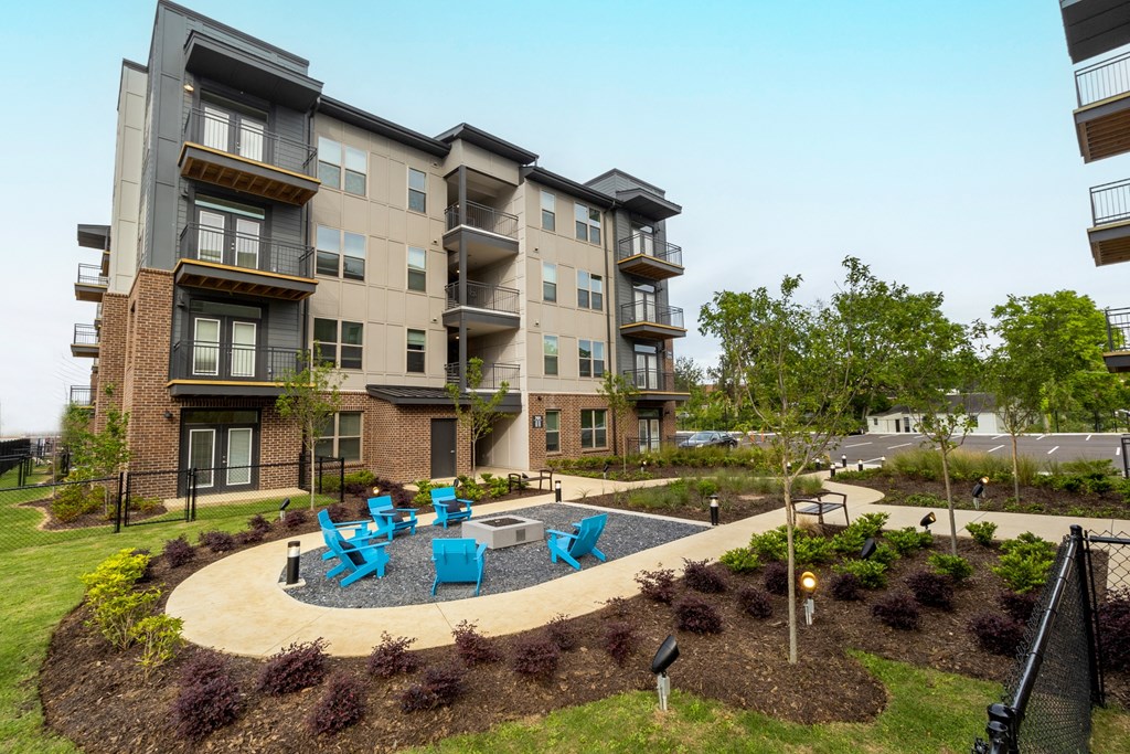 an outdoor patio with blue chairs in front of an apartment building
