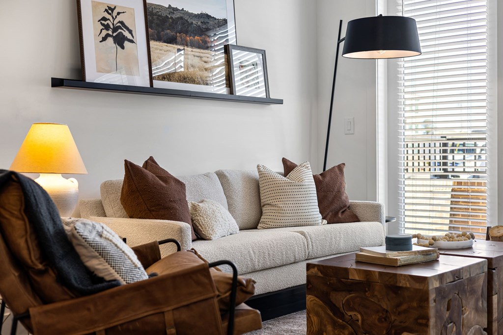 A living room with a white couch, a brown chair, and a lamp.