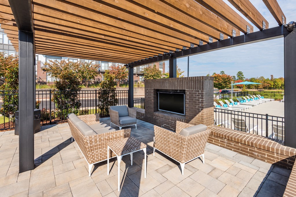 a patio with a fireplace and chairs and a pool