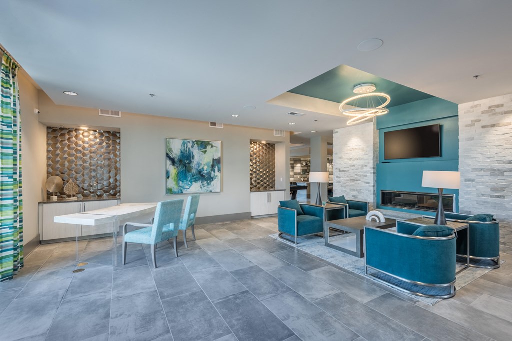 a lobby with blue chairs and tables and a tv
