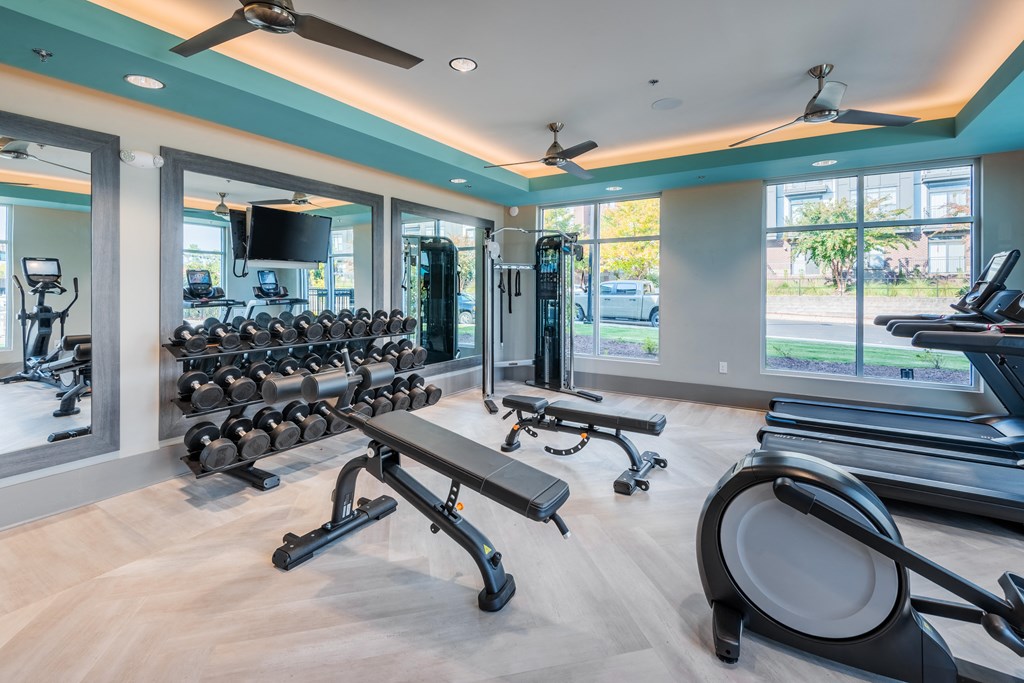 a gym with treadmills and other fitness equipment in a building with windows