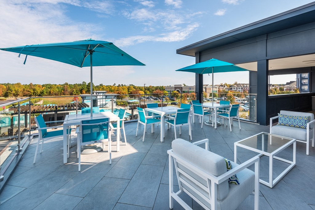 a rooftop patio with tables and chairs and umbrellas