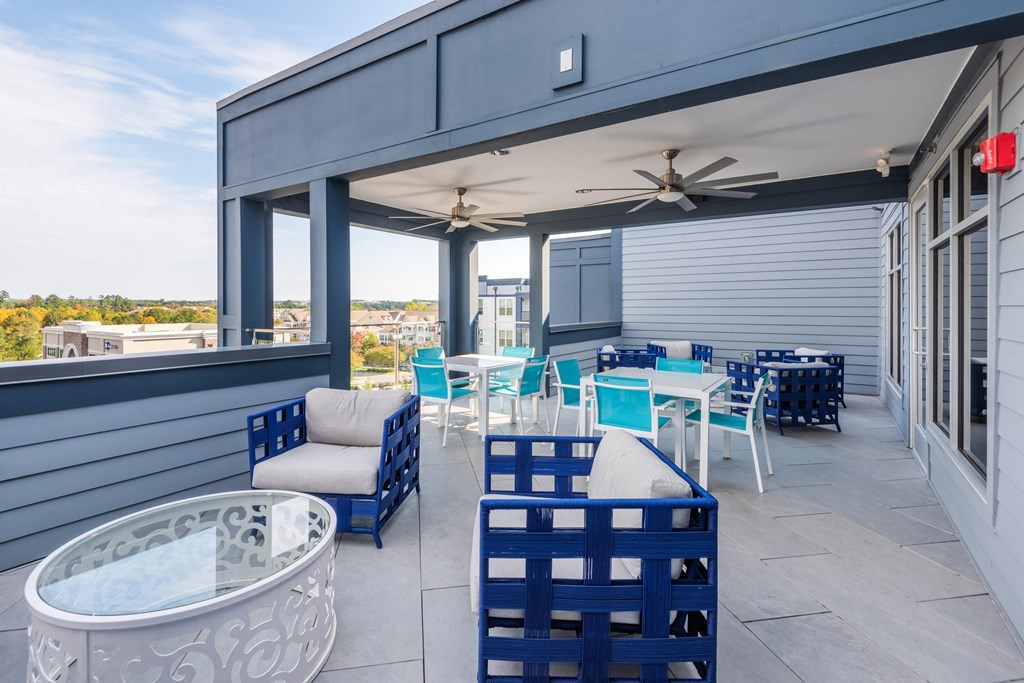 a covered patio with blue chairs and tables and a jacuzzi