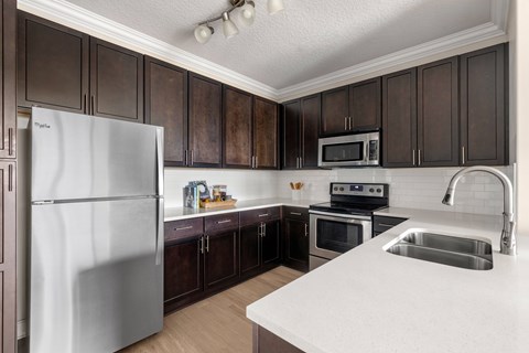 A kitchen with a white counter top and a stainless steel refrigerator.