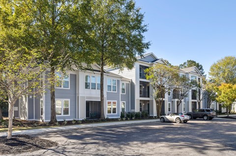 A modern residential building with a parking lot in front.