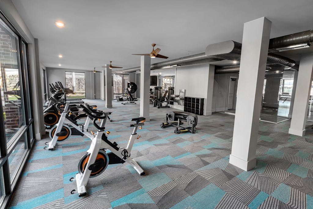 a gym with treadmills and other exercise equipment in a building with windows