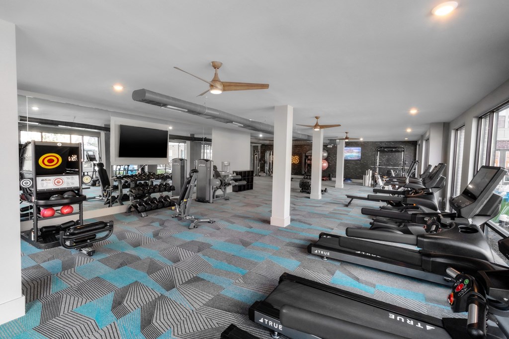 a gym with treadmills and other workout equipment in a building with windows