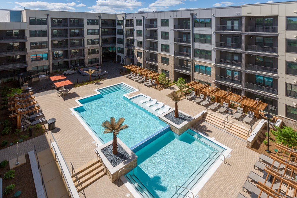 a rendering of a pool with chairs and a building in the background