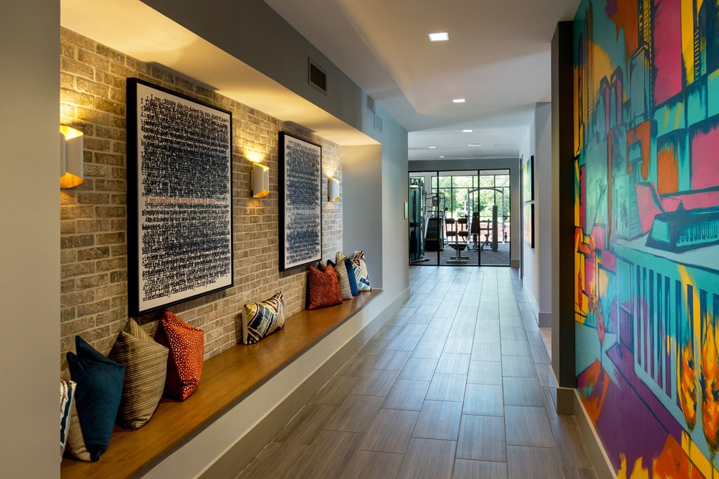 a long hallway with pillows on a bench and a wall with graffiti